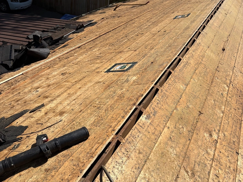 Roof decking inspection during tear-off showing plywood replacement